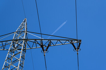 Konventionelle und erneuerbare Energie in einem Bild: Detail eines Strommastes mit Leitungen und...
