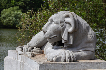 Fototapeta na wymiar Egyptian sphinx stylized cast-iron sculpture of a lion near pond, Kuzminsky park, Moscow
