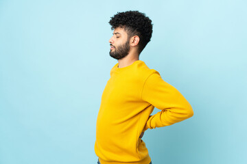 Young Moroccan man isolated on blue background suffering from backache for having made an effort