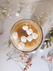 Ice coffee with marshmallows with dry flowers on background