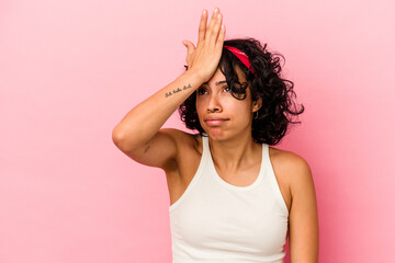 Young curly latin woman isolated on pink background forgetting something, slapping forehead with palm and closing eyes.