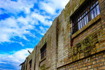 Fototapeta premium old abandoned wall with barred windows and sky