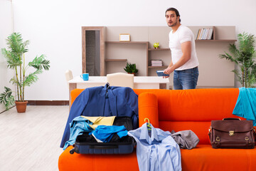 Young man student preparing for trip at home