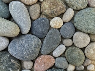 Fototapeta na wymiar Gravel pattern of colored stones. Abstract nature pebbles background. Small sea stones on the ground. Top view