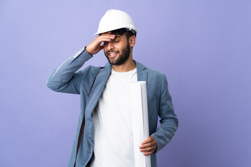 Young architect Moroccan man with helmet and holding blueprints over isolated background smiling a lot