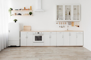 New apartment, modern renovation. White kitchen furniture with utensils, shelves with crockery and...