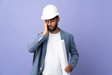 Young architect Moroccan man with helmet and holding blueprints over isolated background with headache