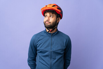 Young Moroccan cyclist man isolated on purple background and looking up - obrazy, fototapety, plakaty