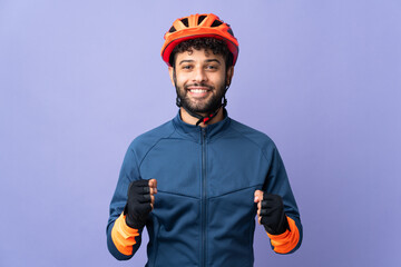 Young Moroccan cyclist man isolated on purple background celebrating a victory in winner position - obrazy, fototapety, plakaty