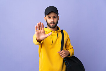 Young sport Moroccan man with sport bag isolated on purple background making stop gesture
