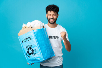 Young Moroccan man holding a recycling bag full of paper to recycle over isolated background...