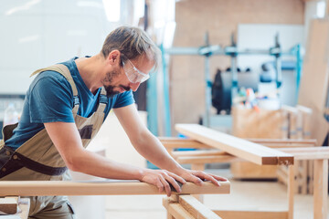 Carpenter sanding piece of wood by hand