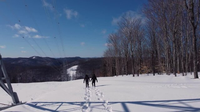 Videography featuring a couple of young and curious documentarian walking near cellular signals towers, in a fresh snow while wearing skiing shoes