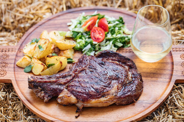 Dry aged steak on a wooden board with potatoes and cherry tomato and lettuce 