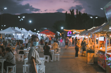 Young women wearing surgical mask touring in night market , Chaing Mai Thailand