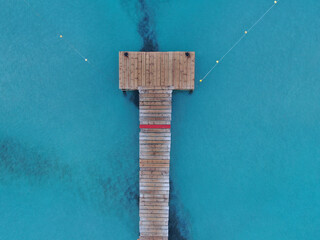 vista aerea de un muelle de madera sobre el mar con el de color azul turquesa en la playa de mallorca	
