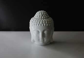 home decor white buddha head on a table. Moody lighting. With room for text.