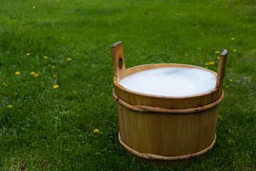 Wooden tub with foam on a green lawn in the countryside