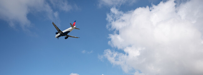 Commercial airplane flying on blue sky with clouds