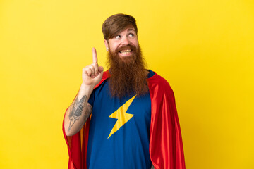 Redhead Super Hero man isolated on yellow background intending to realizes the solution while lifting a finger up