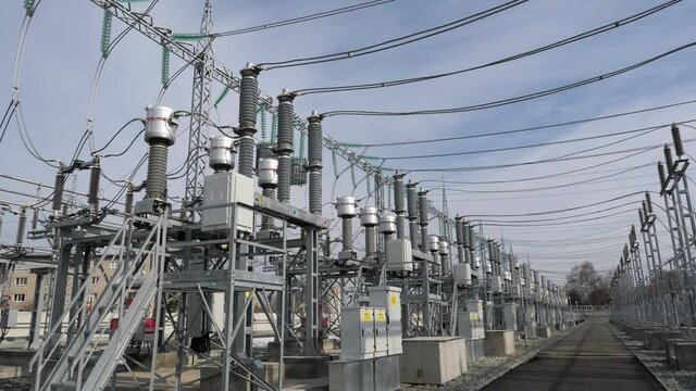 Passway between rows of contemporary equipment at electricity production substation under blue sky with light clouds