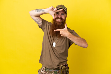 Redhead Military man with dog tag isolated on yellow background focusing face. Framing symbol
