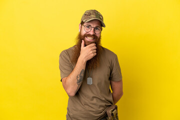 Redhead Military man with dog tag isolated on yellow background with glasses and smiling