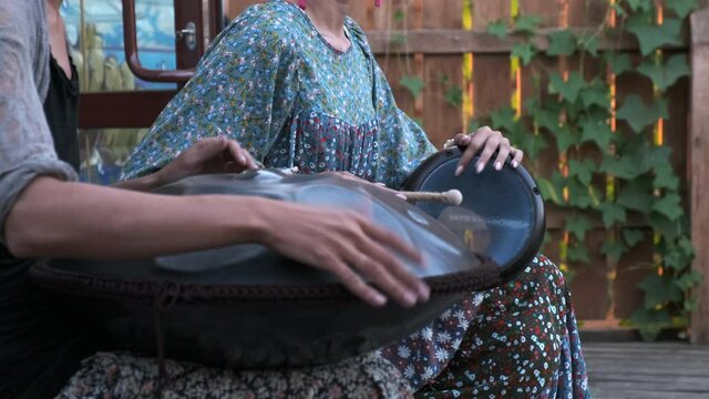 Hands of girls playing percussion instruments: tank drum, djembe