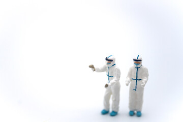 Healthcare and Pandemic Consept. Two doctor miniature figure people wearing Personal Protective Equipment, (PPE) outfit with Infrared Thermo scan on white background.