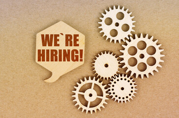 On a paper background, gears and a thought plate with the inscription - We Re Hiring