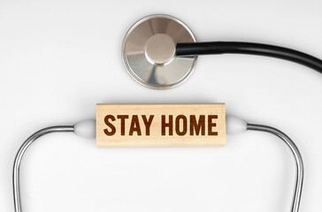 On the table is a stethoscope and a wooden plate with the inscription - STAY HOME