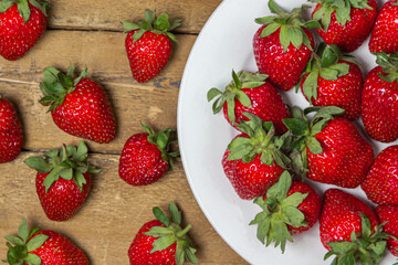 Strawberries in a plate on a wooden table. Ripe fresh strawberries. Healthy diet.