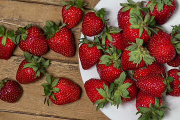 Strawberries in a plate on a wooden table. Ripe fresh strawberries. Healthy diet.