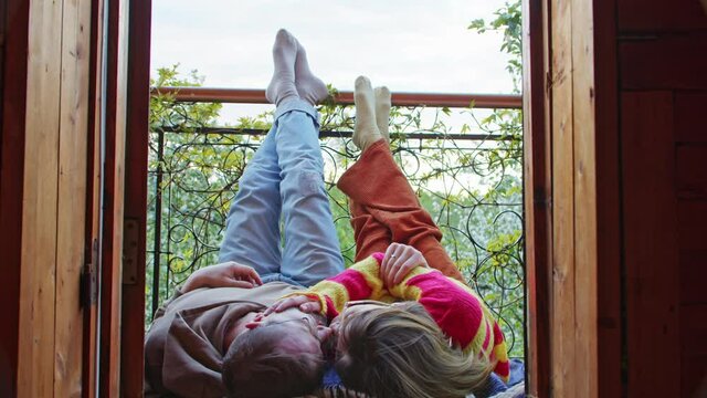 a man and a woman kiss on the balcony of the house or in a cozy hotel overlooking nature, raising their legs up and enjoying each other