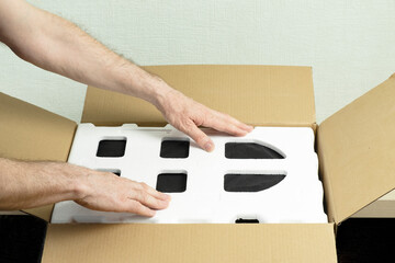 Male hands place the foam sealant in a cardboard box. Concept delivery, packaging