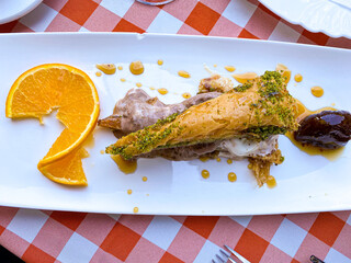 Delicious traditional dessert turkish baklava in plate with fruit on table