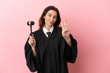 Middle aged judge woman isolated on pink background happy and counting four with fingers