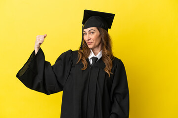 Middle aged university graduate isolated on yellow background doing strong gesture