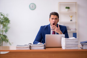 Naklejka premium Young businessman and too much work in the office
