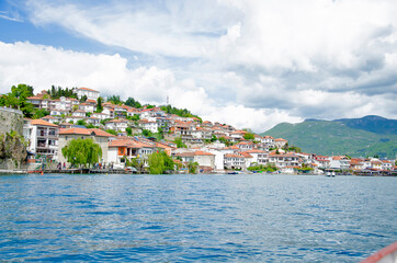 Fototapeta premium Impressively beautiful view from lake with boats tree, stones, beach, mountain on clear blue sky
