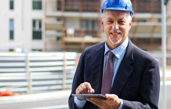 Senior Engineer Man In Suit And Helmet Working On Tablet Pc