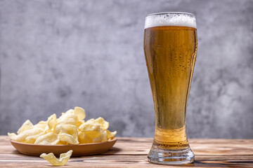 a glass of beer and chips on a wooden background