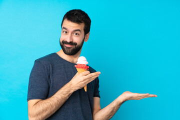 Young man with a cornet ice cream over isolated blue background extending hands to the side for...