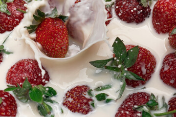 Ripe strawberries fall into the cream. Splashes of milk.