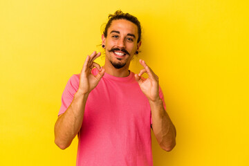 Young caucasian man with long hair isolated on yellow background cheerful and confident showing ok...