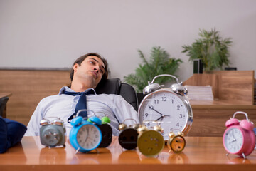 Young male employee sleeping in the office in time management co