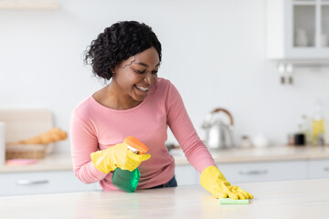 Pretty african american young woman in rubber gloves cleaning table