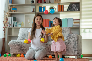 Asian family mother and child daughter are playing colorful balls
