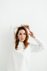 Fototapeta premium b girl in a white sweater holds her hands above her head