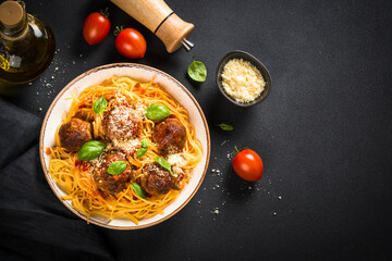Pasta with Meatballs in tomato sauce, basil and parmesan on dark stone table. Top view with copy space.